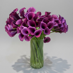 Bouquet of purple flowers in a clear vase on a wooden surface