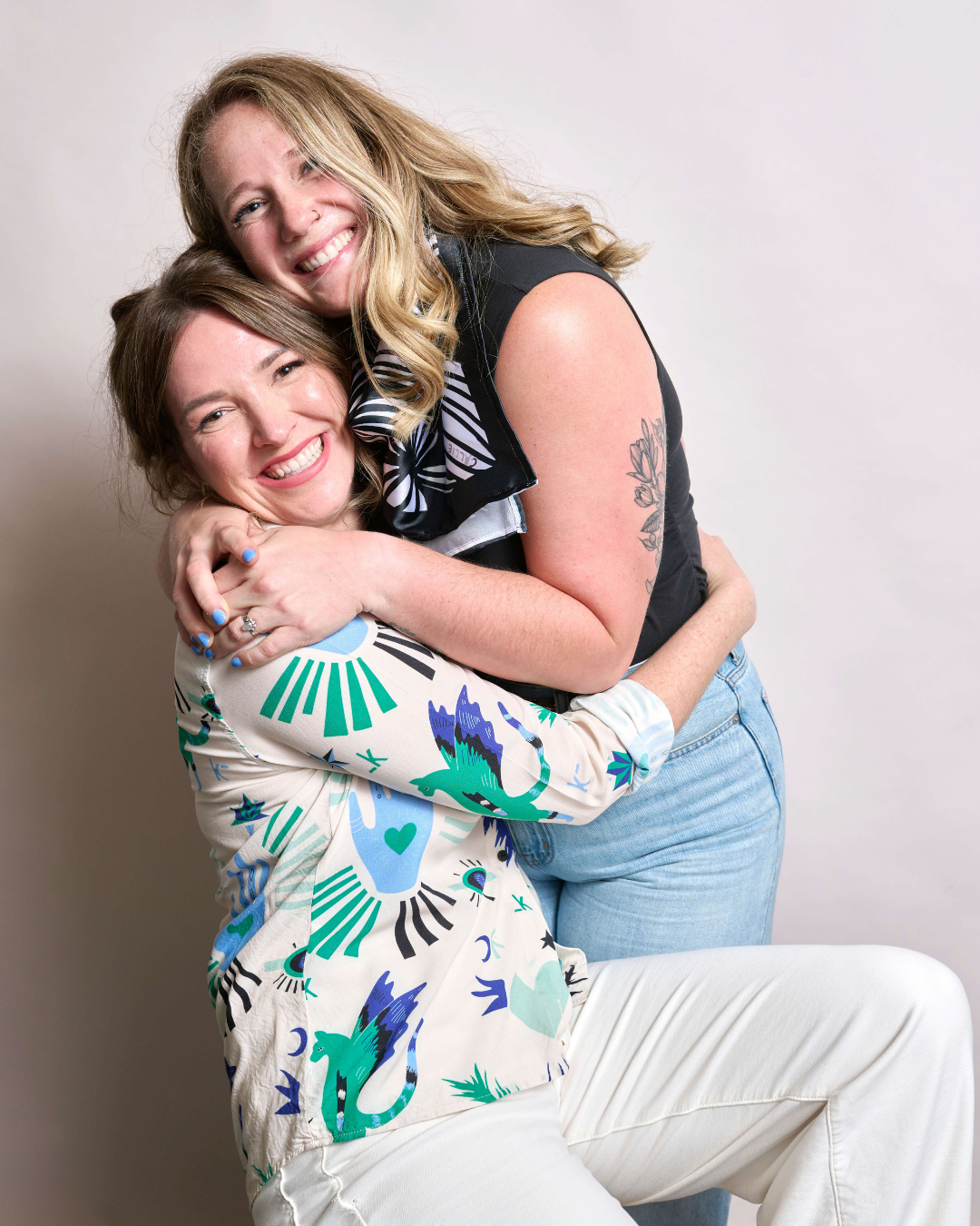 Two women hugging each other against a plain background